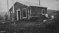 Uniformed man in front of log cabin signal station at Richardson, Alaska, 1914 (AL+CA 4052).jpg
