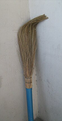 a typical Indian broom leaned upside-down against a wall