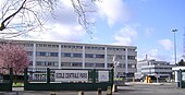 fotografia a colori di un edificio bianco a tre piani dietro il cancello d'ingresso.