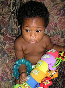 Photo en couleur montrant un jeune enfant noir jouant avec un objet de couleur