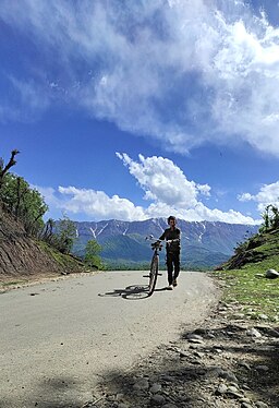 An exhausted kid with an oversized, old bicycle