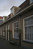 Woning in rijtje van vier woningen van vrijwel identieke opzet, in 1852 als belegging achter zijn woning aan het Oosteinde gebouwd door de aardewerkfabrikant Smink, opgetrokken in een sobere traditionele bouwtrant. Het is met de andere woningen in het rijtje van belang als goed voorbeeld van arbeiderswoningbouw uit de tweede helft van de 19de eeuw.