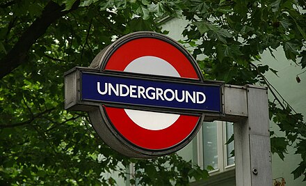 London Underground stations are identified with signs like these, and Overground stations have a similar symbol with an orange circle. National Rail stations have a different "double-arrow" symbol.