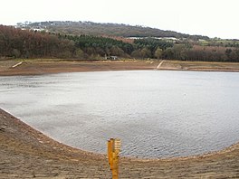 Reservoir pada volume rendah menunjukkan batu-batu di sekitarnya, dengan pohon-pohon di kejauhan