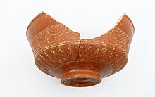 Photographie en couleurs d'un récipient antique en céramique brune.