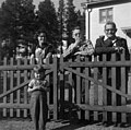 Nomadskolan, lærer Carl Johansson med familie står ved et gjerde, del av bolig i bakgrunnen - Norsk folkemuseum - NF.05328-024.jpg
