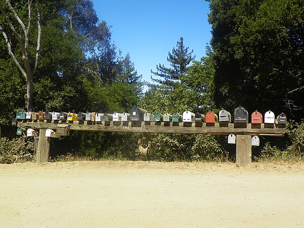 A large pulley hangs from a beam supporting a row of mailboxes on Palo Colorado Canyon Road.