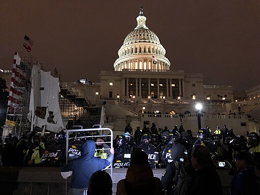 Riot police and protester outside United States Capitol at evening 20210106