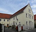 Residential house, attached side building and further side building of a former four-sided courtyard and keystone in the courtyard wall