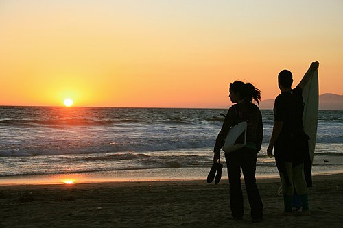 A young couple watching the sunset on a Los Angeles beach with surfboard in hand Venice, California Beach.jpg