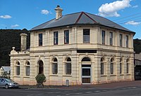 Former bank at 112 Main Street Zeehan. It was constructed by the Commercial Bank of Tasmania and opened in 1899.[33] It was merged into the English, Scottish and Australian Bank in 1921 and the ANZ Bank in 1970, but the branch was closed by ANZ in late 2016.