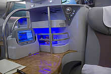 Business class seats (pictured aboard an Emirates aircraft) in aircraft usually provide more space and facilities than the standard class. Emirates business class A380 seat bar.jpg