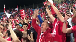 Football fans jumping up and down in the stadium singing a chant against opposing fans
