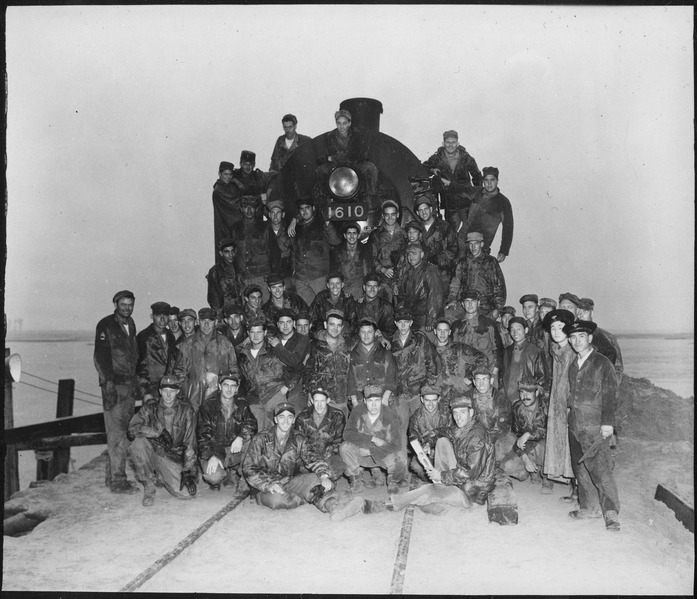 File:Officers and men of the 62nd Engineers stand in front of the first train to cross the new railroad bridge which they... - NARA - 531382.tif