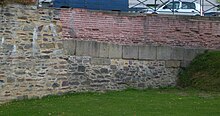 Photoraphie d'un pan de muraille romaine à Rennes. On remarque différents styles de construction, utilisant des pierres, pierres de taille et tuiles.