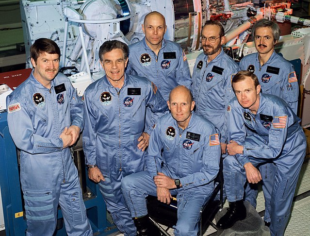 Front row (seated): C. Gordon Fullerton, Roy D. Bridges Jr. Back row (standing): Anthony W. England, Karl G. Henize, F. Story Musgrave, Loren W. Acton