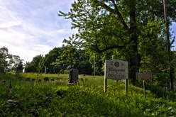 A wooden sign "Welcome to Ossining" and a metal sign for Sparta Cemetery