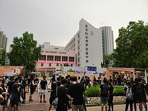 Lennon Wall set up by large crowd outside a high school