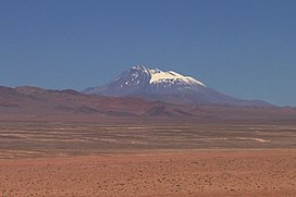 Uma montanha plana-cônica coberta de neve se eleva acima de um cume