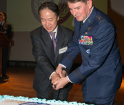 잔-마크 주아스 미국 공군 대장과 and 고지 토지마(왼쪽), 일본 외무성 북미국장이 2013년 유엔군 후방사령부 유엔 기념일 파티에서 함께 케이크를 자르는 모습.