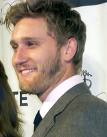 A 28-year-old man with a beard smiles to the left of the camera.