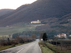 Pente montagneuse couverte d'une végétation méditerranéenne et au milieu de laquelle est située une abbaye de pierre blanche.