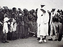 le roi et la reine en costume clair saluent une haie de Congolais