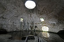 Bare concrete dome interior today called the Temple of Mercury with two square windows halfway up the dome on the far side, a circular oculus⁠(d) at the top, and a water level that reaches up to the base of the dome