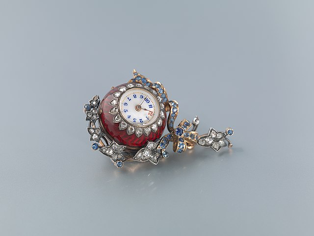 A gold, diamonds and sapphires red guilloché enamel "Boule de Genève", a type of pendant watch used as an accessory for women. An example of an object