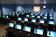 Dezenas de telas de computador azuis brilhantes em uma grande sala.