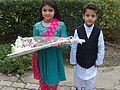 Pakistani girl and boy with flowers, showing off typical shalwar kameez