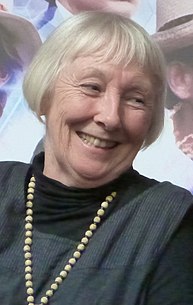 A 71-year-old woman with white hair smiling to the right of the camera.