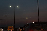 A green coloured Delhi Transport Corporation CNG bus in the middle of the road