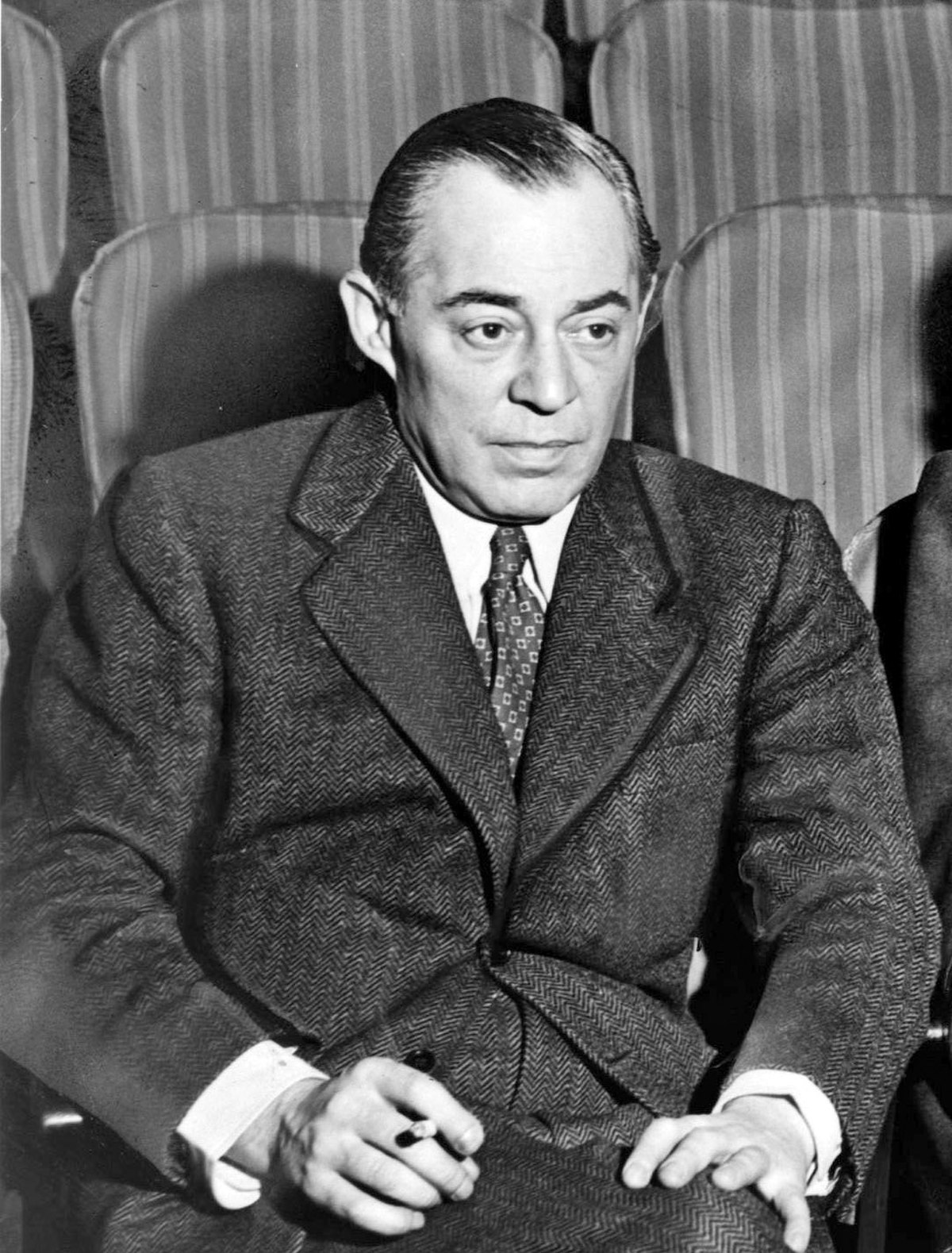 Photo of Rodgers in middle age， seated in a theatre， wearing a suit and holding a cigarette