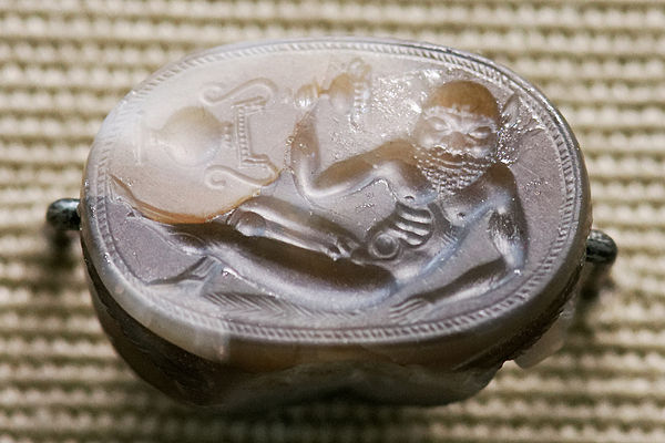 Reclining satyr, Etruscan c. 550 BC, 2.2 cm wide. Note the vase shown "sideways"; it is characteristic of early gems that not all elements in the desi