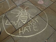 "Love not hate" chalk graffiti on the pavement in St Ann's Square, featuring the worker bee symbol. St Ann's Square tributes and memorials, Manchester, May 2017 (15).JPG