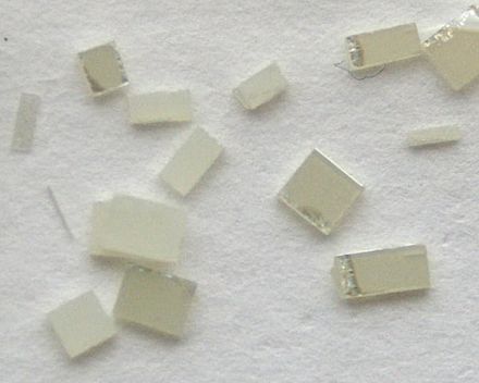 Synthetic single crystals of TiO2, ca. 2–3 mm in size, cut from a larger plate.