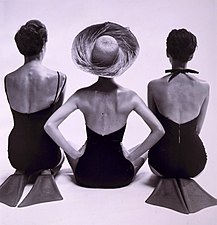 Vue de dos de mannequins en maillot de bain, deux agenouillés portant des palmes de natation, et un assis. Photographie de Toni Frissell publiée dans Harper's Bazaar, janvier 1950.