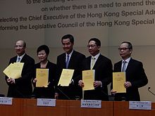 Four men and one woman displaying copies of a report