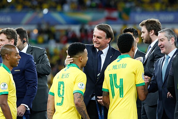 Militão (number 14) shakes hands with President of Brazil Jair Bolsonaro and President of CONMEBOL Alejandro Domínguez after winning the 2019 Copa Amé