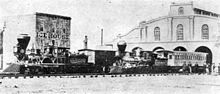 Photographie de deux trains tirés par des locomotives du XIXe siècle devant un bâtiment portant l'inscription « Ice House ».