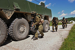 Soldiers take cover beside a Patria AMV Croatian soldiers take cover beside a military vehicle as they enter a village during a raid as part of Immediate Response 2012 at the Slunj Training Area, Croatia, June 5, 2012 120605-A-KH850-016.jpg