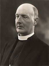 bald white man in clerical collar and black clothes