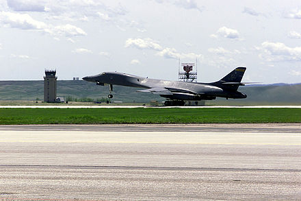 A B-1B Lancer takes off from Ellsworth AFB in front of the control tower and radar.
