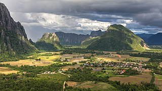 Karst peaks and green paddy fields under a stormy sky, South view from Mount Nam Xay, Vang Vieng, Laos