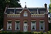 Boerderij, bestaande uit een woonhuis met aangebouwd bedrijfsgedeelte, gebouwd op een kunstmatige verhoging. In de gevel van het huis zijn elementen van Neo-Renaissance verwerk