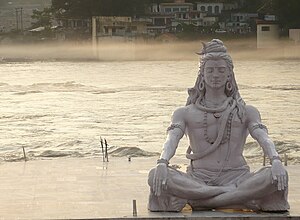 פסלו של האל שיווה עושה מדיטציה מעל נהר הגנגס.