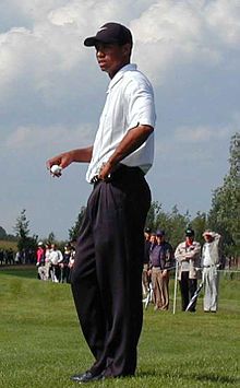 Ein Golfspieler mit schwarzer Mütze auf dem Kopf hält einen Ball in der rechten Hand.