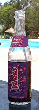 бутылка Vimto с трубочкой на столе возле бассейна в солнечный день