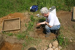 Ken Feder recovering the tip of a stone spearpoint at a 1,000-year-old archaeological site in West Simsbury, Connecticut. Archaeologist Ken Feder conducting an excavation in West Simsbury, Connecticut..JPG